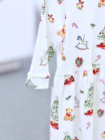 White knit fabric with festive Christmas print featuring teddy bears, rocking horses, and candy canes