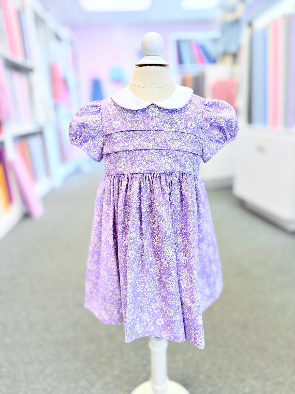 Purple floral fabric made into a child's dress with white Peter Pan collar