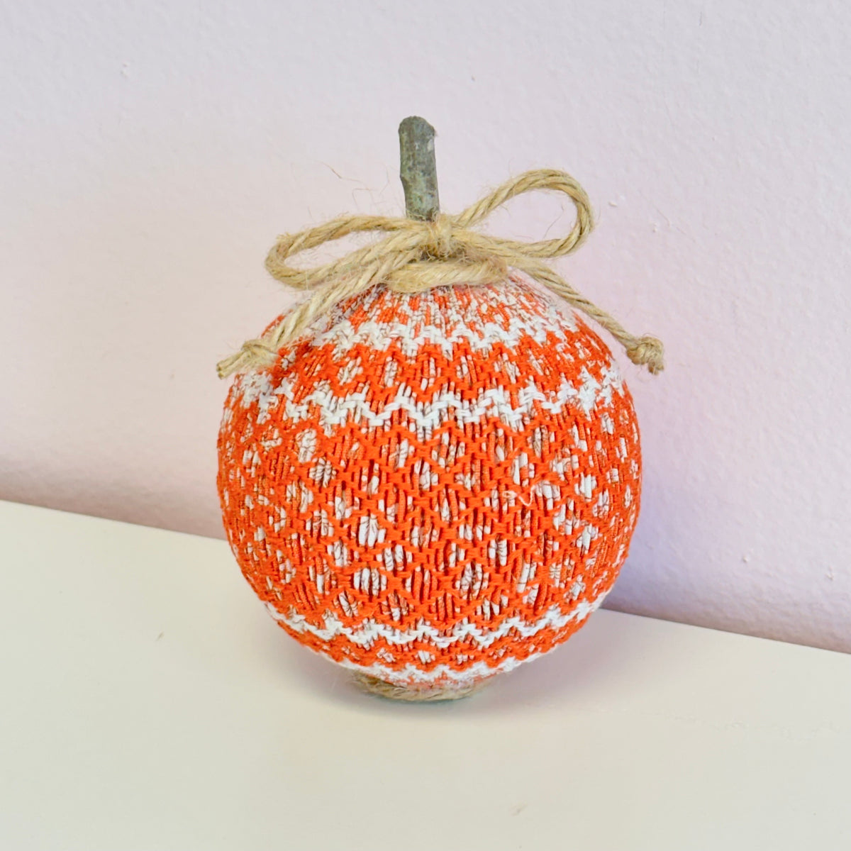 Orange and white smocked fabric pumpkin with twine bow and stem