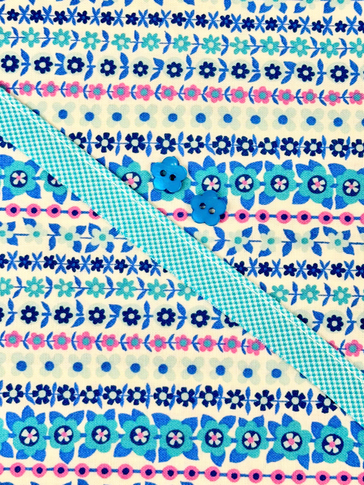 Louise Dress Kit with floral stripe fabric in blue and pink, teal ribbon, and flower buttons