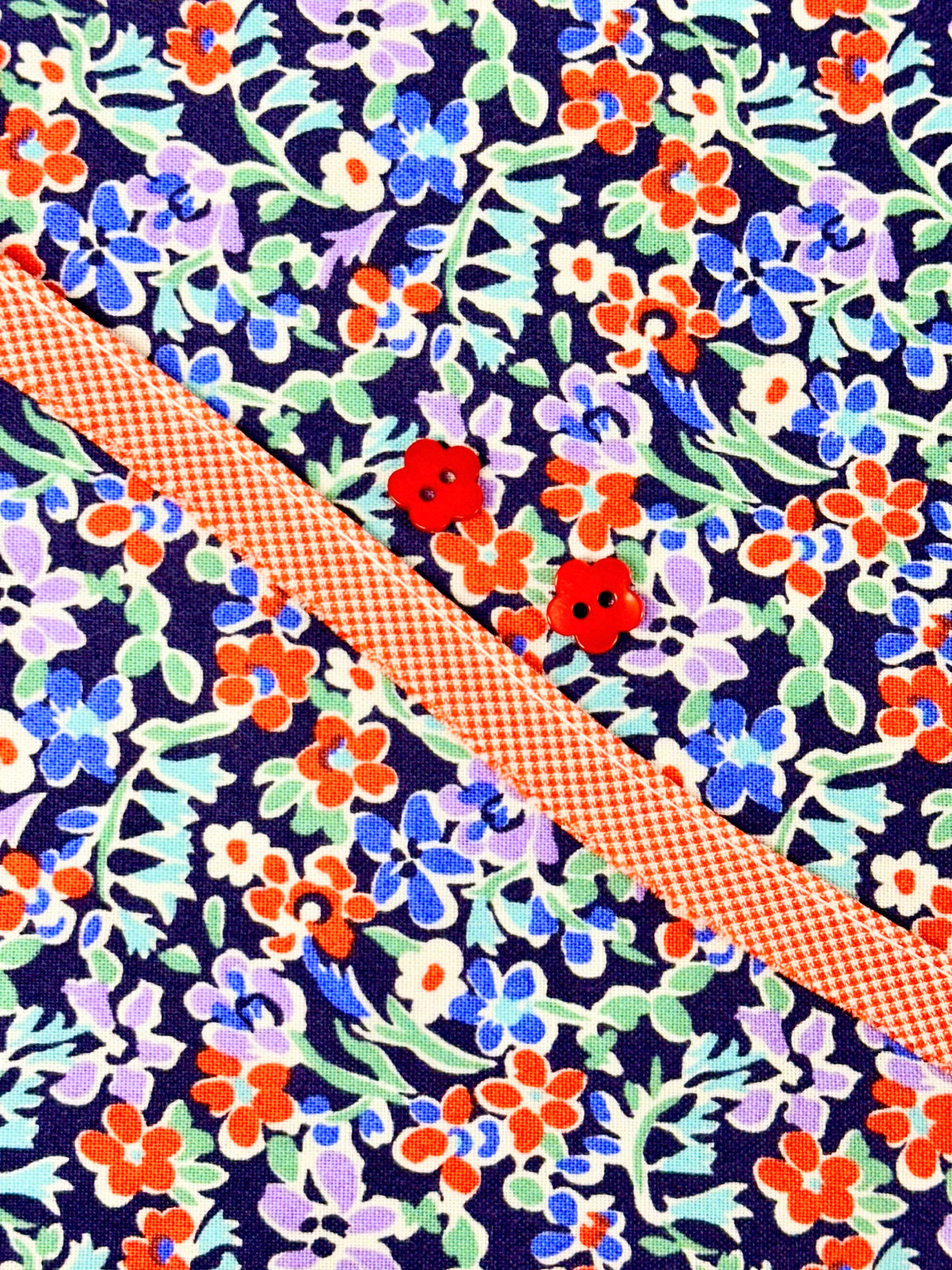 Navy floral fabric with orange gingham ribbon and two red flower buttons