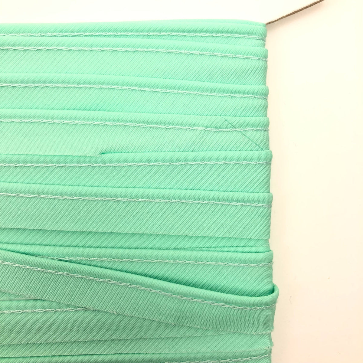 Mint green piping trim folded in layers showing stitched edges
