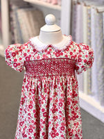 Red floral smocked girls dress with puff sleeves and white peter pan collar on mannequin