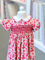 Child's smocked floral dress in red and pink on a white mannequin