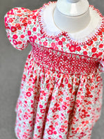 Red floral smocked toddler dress with white ruffle collar and puff sleeves on mannequin