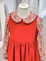 Red children's pinafore dress with floral Peter Pan collar blouse on mannequin
