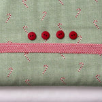 Green candy cane print fabric with red ribbon trim and four red buttons