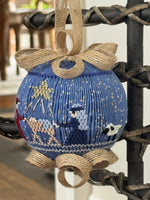 Blue smocked Christmas ornament with nativity scene, jute ribbon bow, star and sheep details