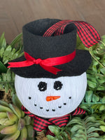 Smocked snowman ornament with black top hat, red ribbon, and buffalo plaid accents