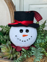 Smocked white snowman ornament with black top hat, red plaid scarf, and carrot nose
