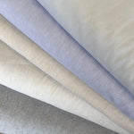 Folded fabric swatches in light blue, cream, and gray chambray solids