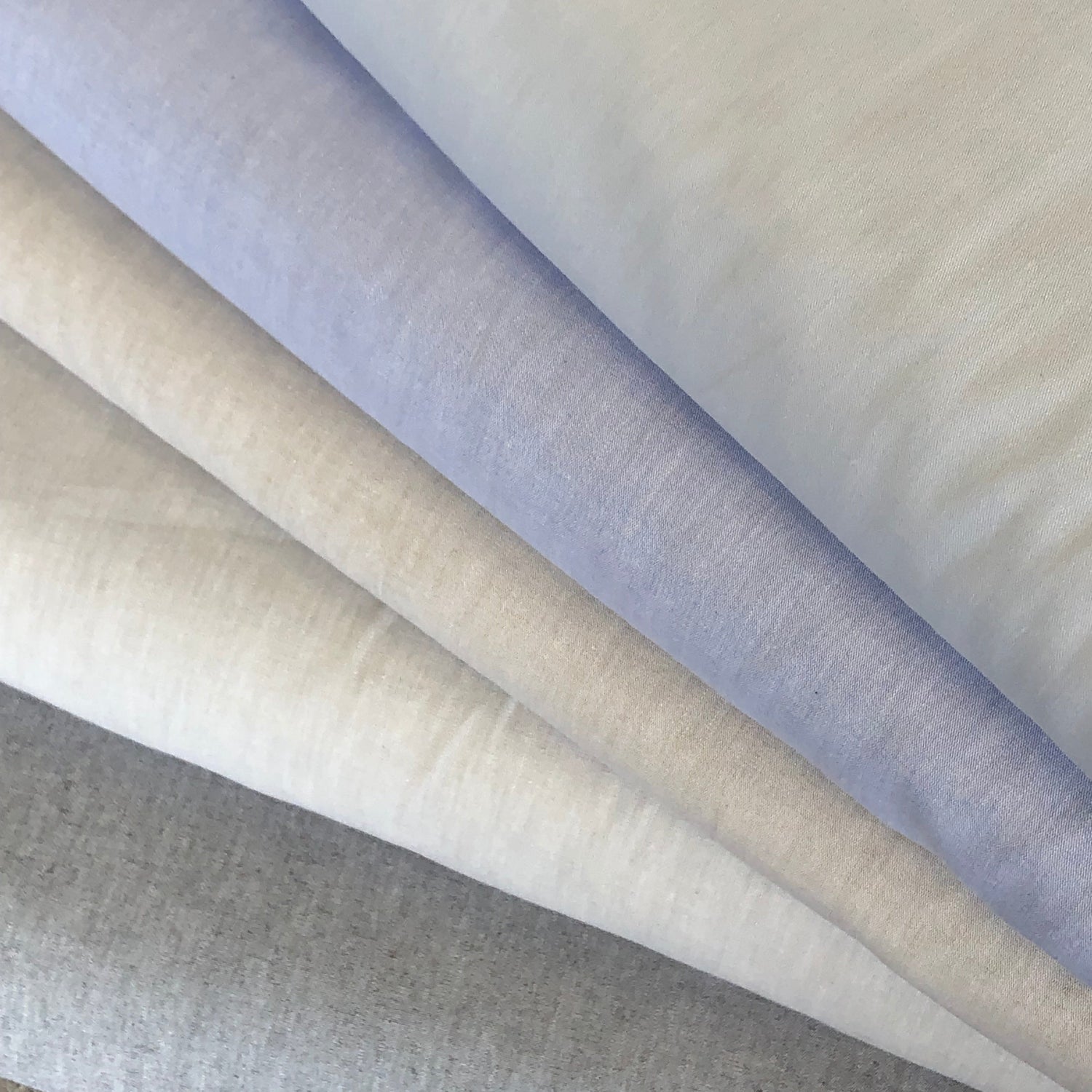 Folded fabric swatches in light blue, cream, and gray chambray solids