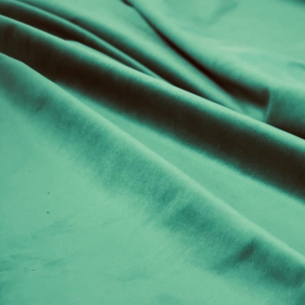 Draped teal velveteen fabric with soft folds showing smooth, plush texture