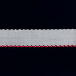 White cotton edging trim with red scalloped embroidered border on dark background