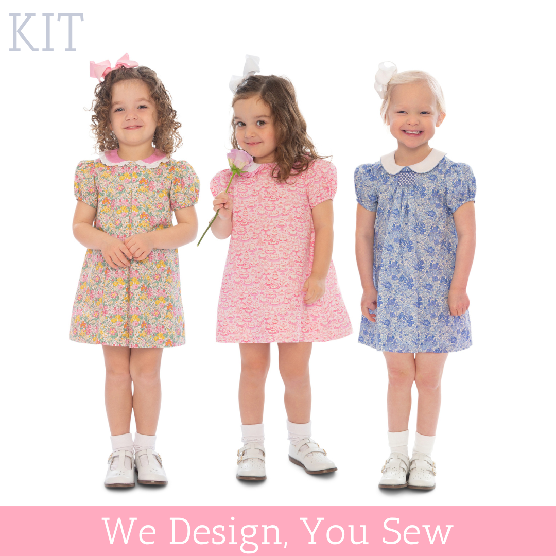 Three toddler girls wearing floral, pink, and blue short-sleeve Carol Dress Kit designs.