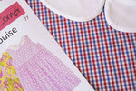 Red, white, and blue gingham check fabric remnant beside a sewing pattern