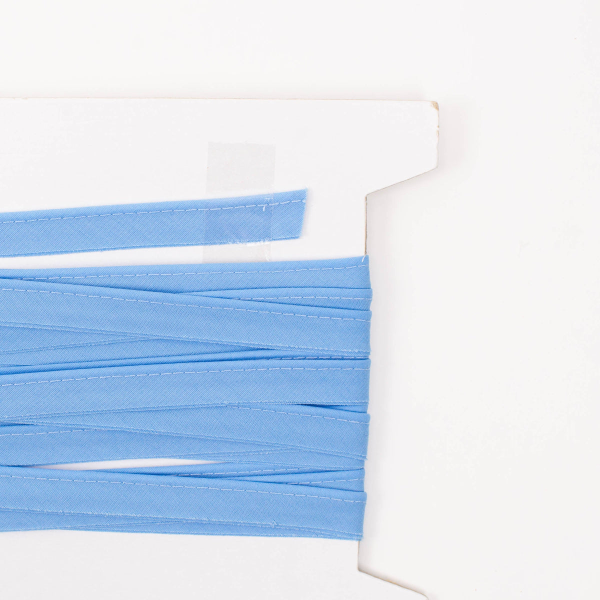 Light blue folded piping trim wound on a white cardboard spool