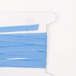 Light blue folded piping trim wound on a white cardboard spool