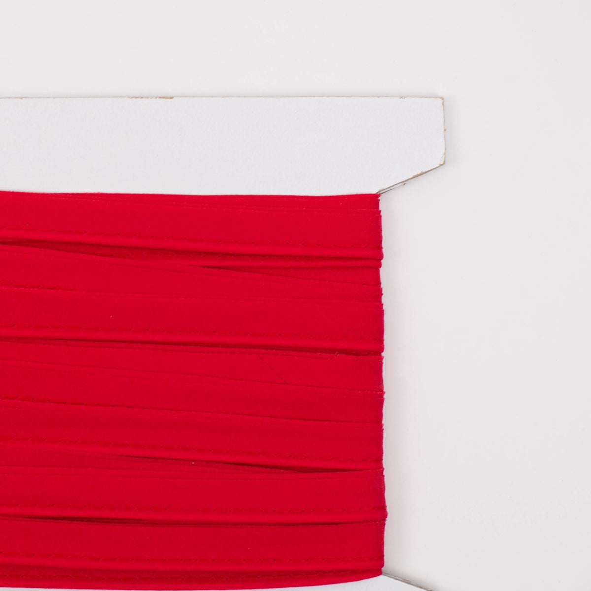 Red piping trim wound on a white cardboard spool