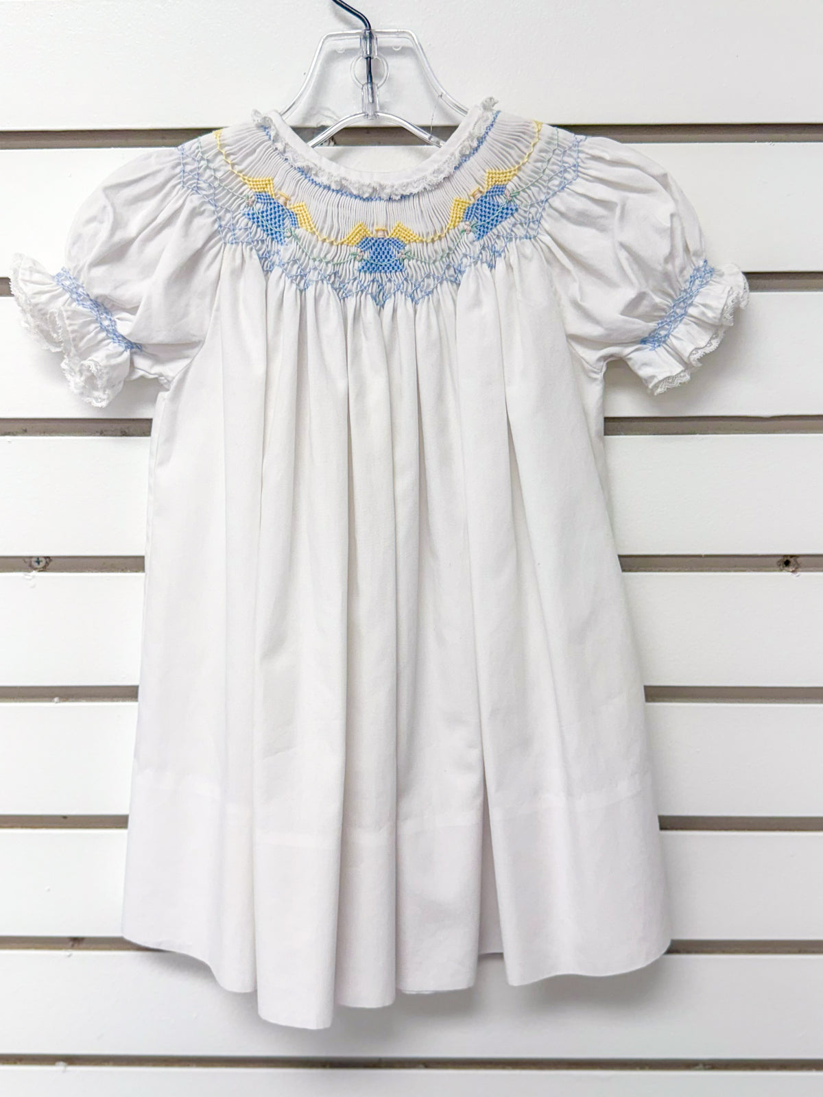 White smocked bishop dress with blue and yellow embroidery, puff sleeves, lace trim