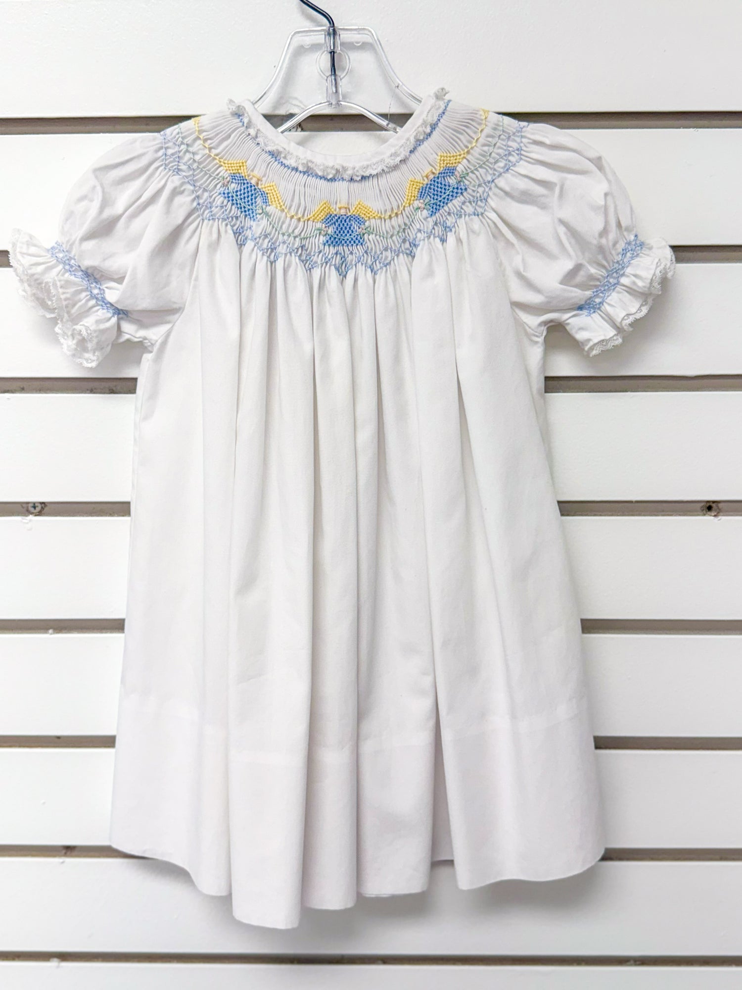 White smocked bishop dress with blue and yellow embroidery, puff sleeves, lace trim