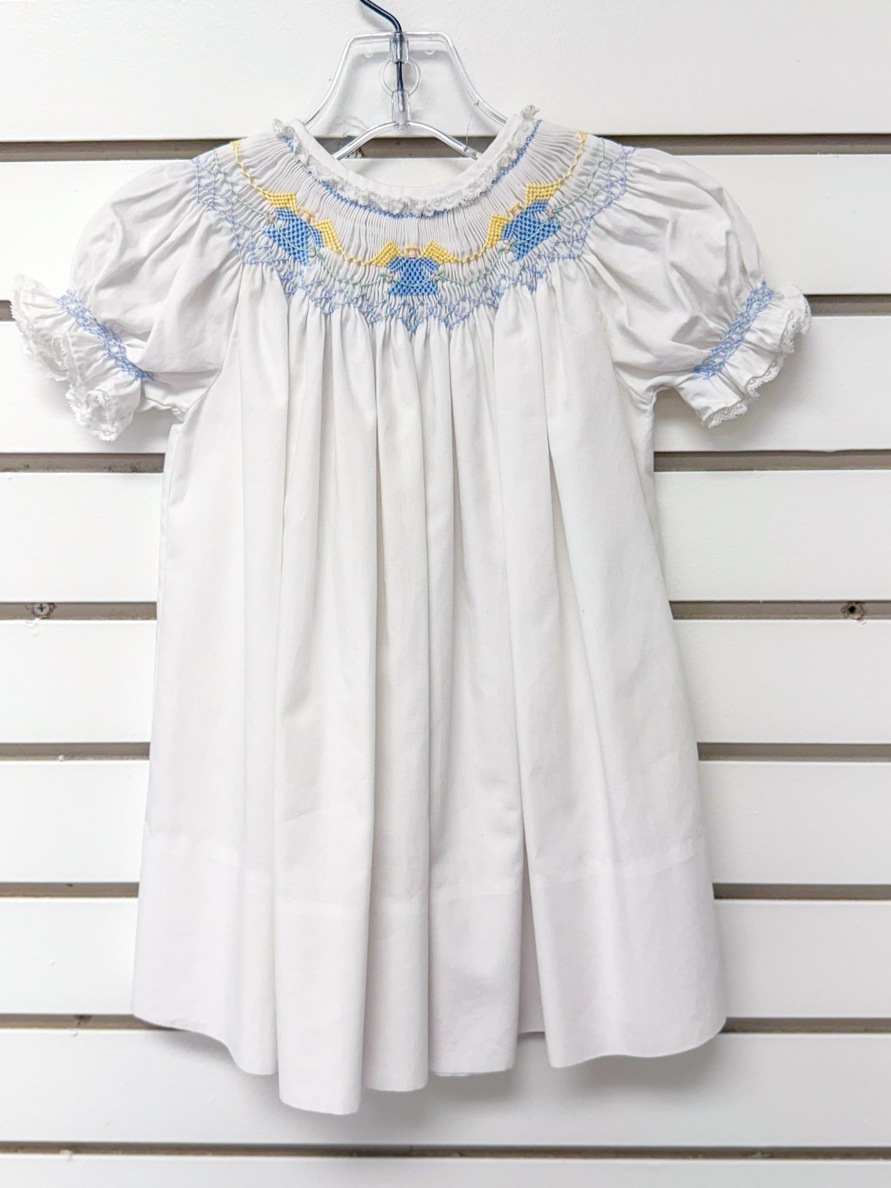 White smocked bishop dress with blue and yellow embroidery, puff sleeves, lace trim