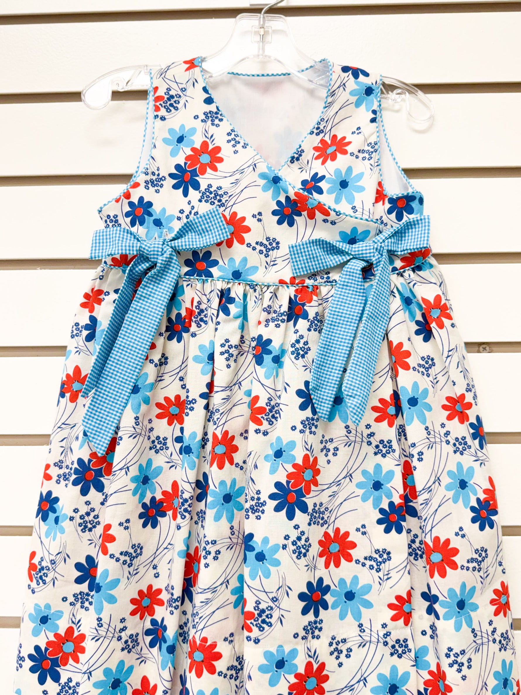 Girl's white floral sundress with red and blue flowers and blue gingham bow sash