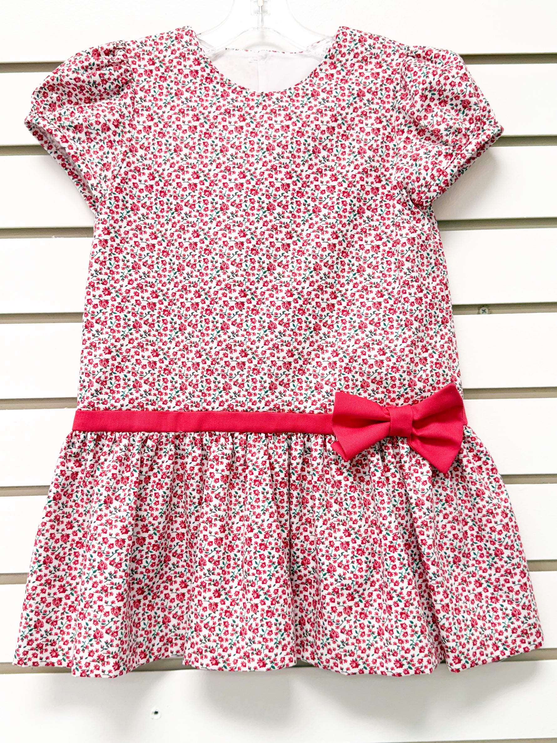 Girl's white drop-waist dress with red floral print, short sleeves, and red bow belt
