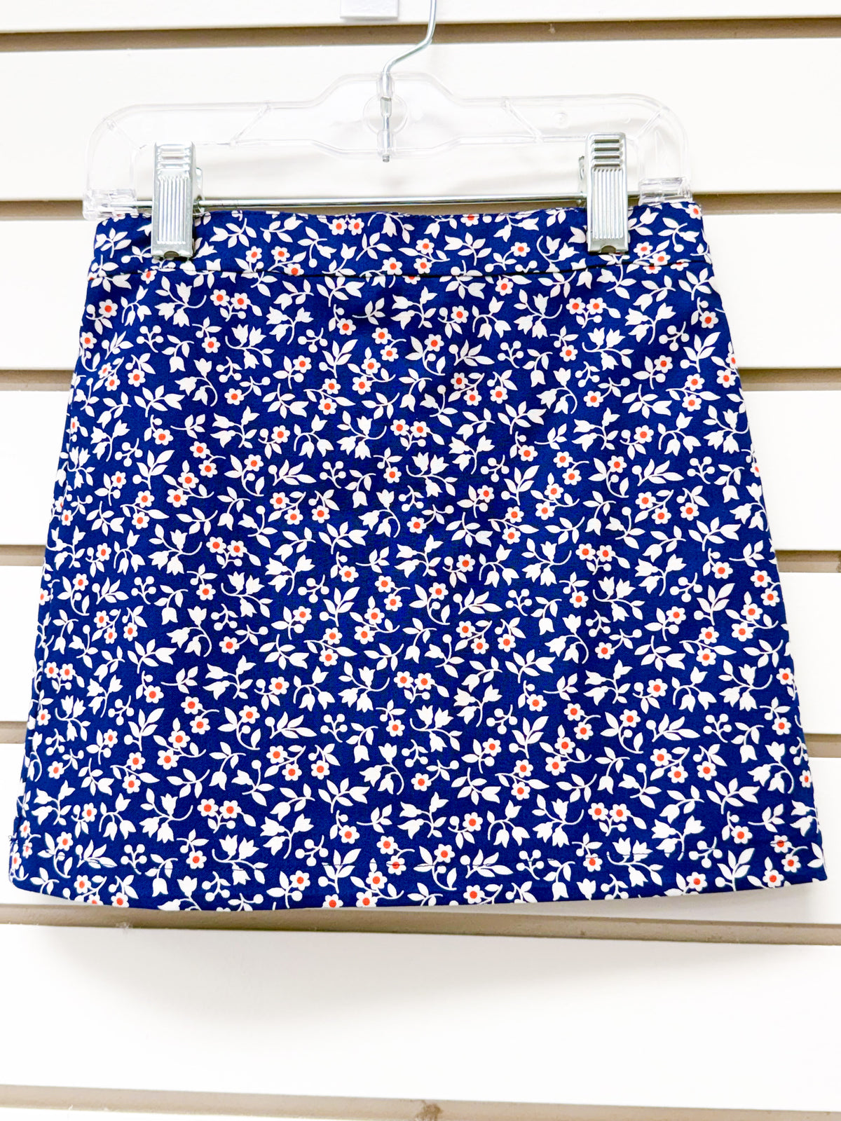 Navy blue mini skirt with white floral and leaf print, small orange flower accents, size 3