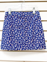 Navy blue mini skirt with white floral and leaf print, small orange flower accents, size 3