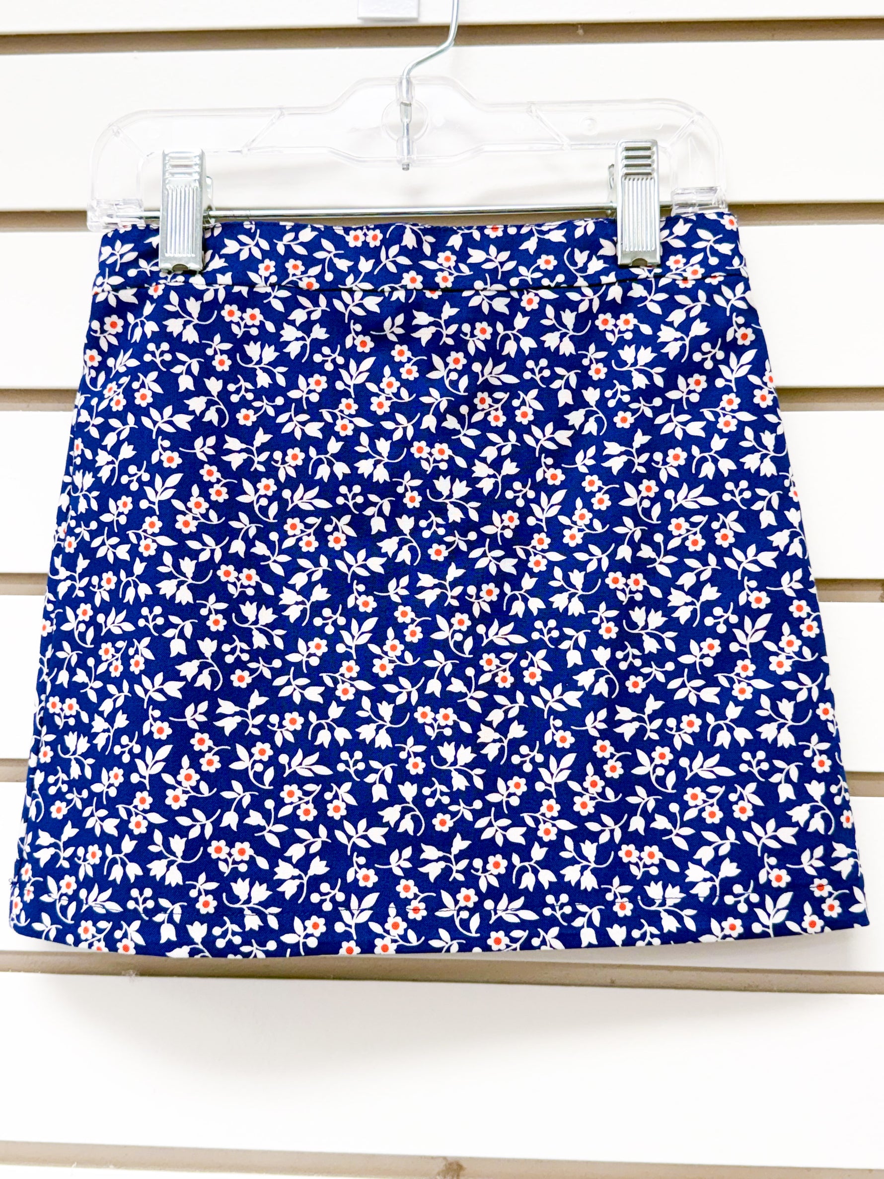Navy blue mini skirt with white floral and leaf print, small orange flower accents, size 3
