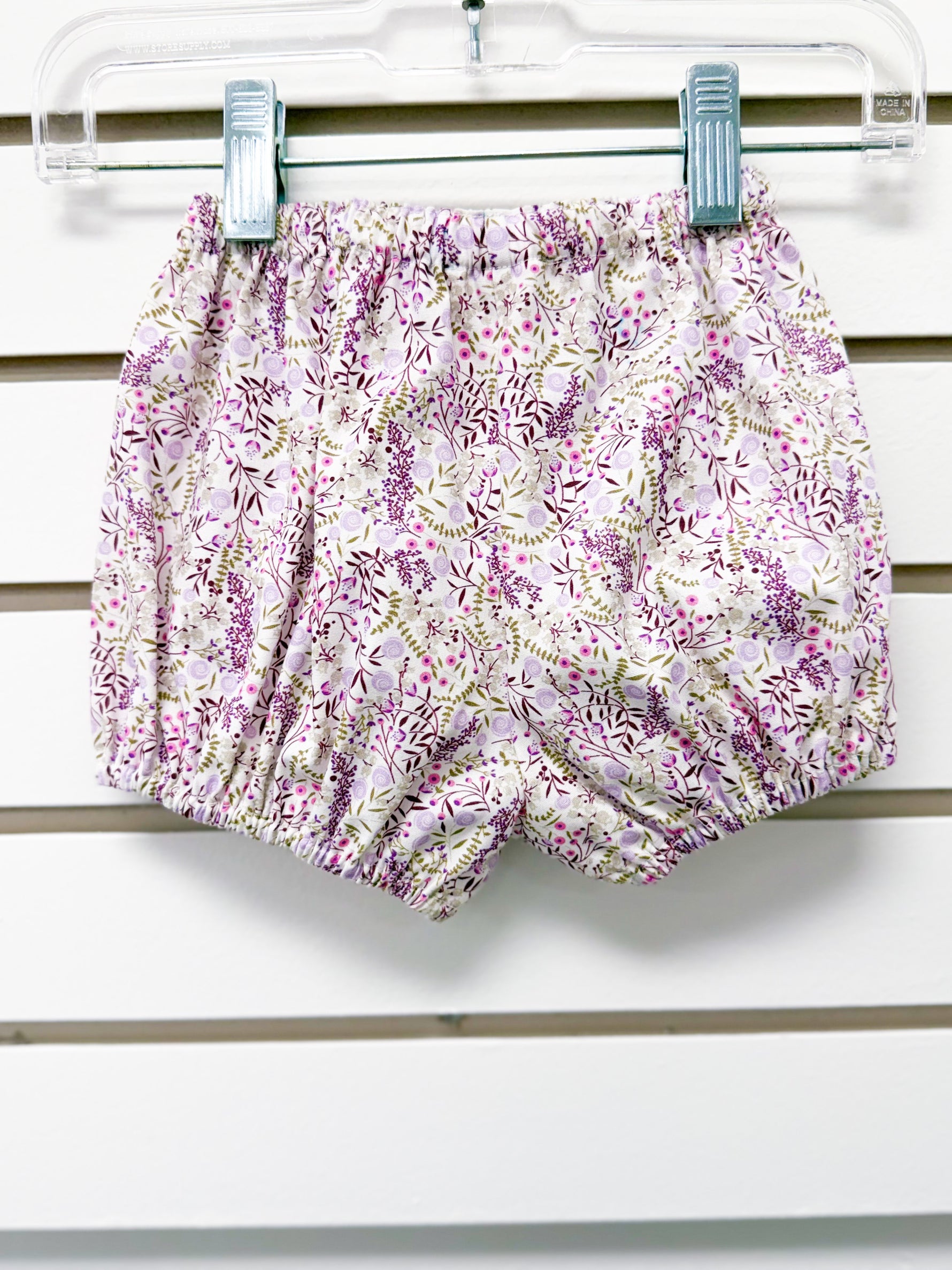 Baby bloomer shorts in white floral print with purple and pink flowers, elastic waist and legs