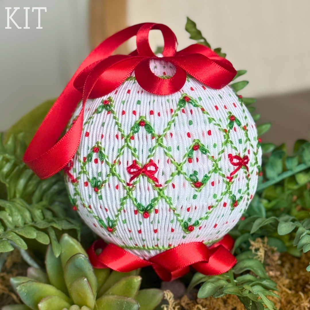 White smocked Christmas ornament with green diamond pattern, red bows, and satin ribbon