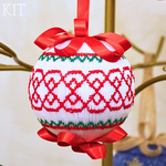 White smocked Christmas ball ornament with red lattice and green trim, red satin bows
