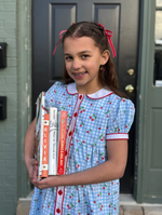 Girl in blue gingham cherry dress with white collar, red trim, holding books