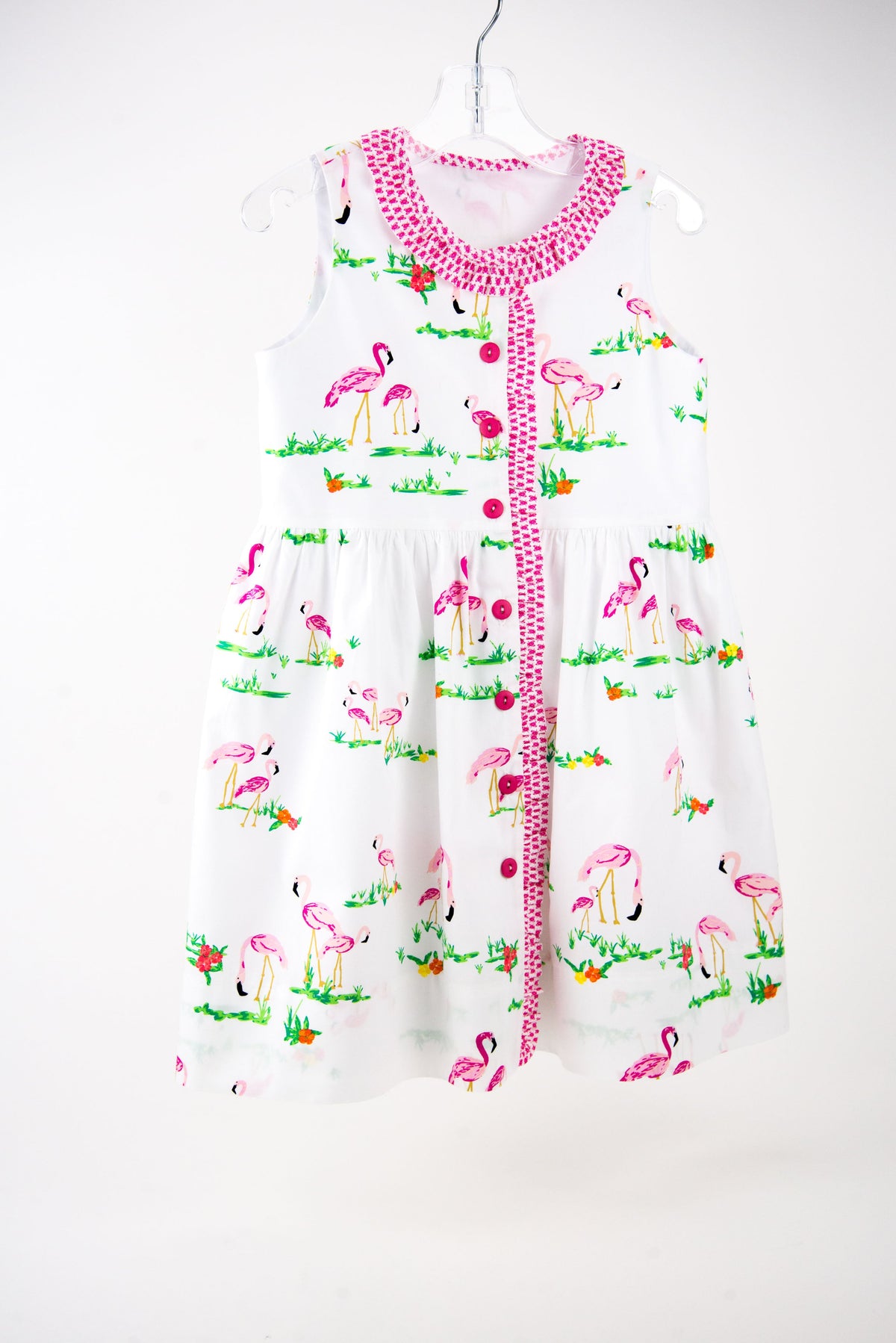 White children's dress with pink flamingo print and pink button front closure