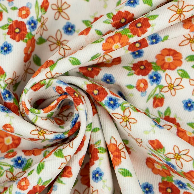 White corduroy fabric with orange, blue floral print and green leaves, swirled display