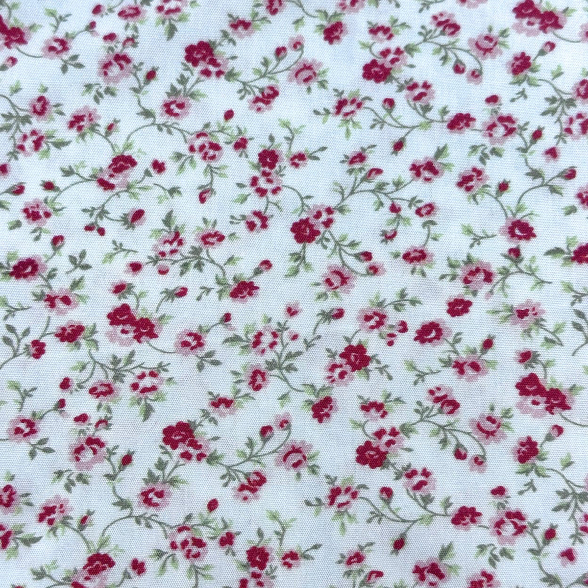 White cotton fabric with crimson and pink rose floral print and green vines