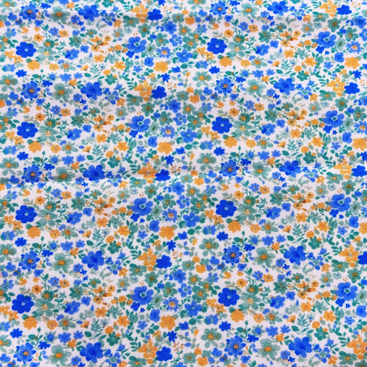 White cotton fabric with small blue, orange, and green ditsy floral print pattern.
