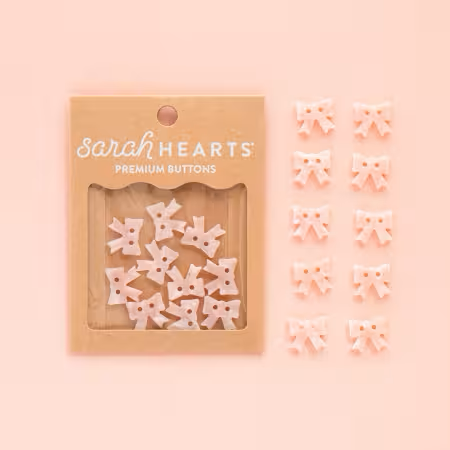 Pink bow-shaped two-hole buttons in packaging by Sarah Hearts, 10-pack