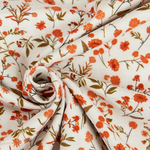 White corduroy fabric with orange floral print, swirled to show texture and pattern