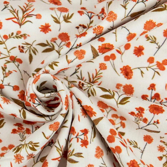 White corduroy fabric with orange floral print, swirled to show texture and pattern