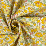 Yellow floral poplin fabric with pink and mint flowers on white background, swirled