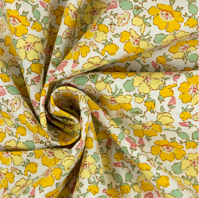 Yellow floral poplin fabric with pink and mint flowers on white background, swirled