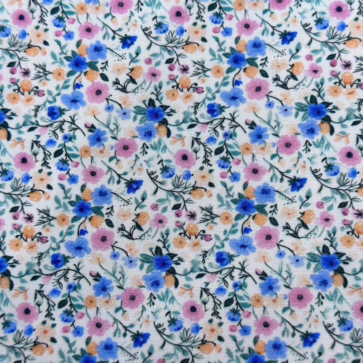 White cotton fabric with small blue, pink, and orange floral ditsy print pattern