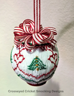 White smocked Christmas ornament with red hearts, green tree, and striped ribbon bow