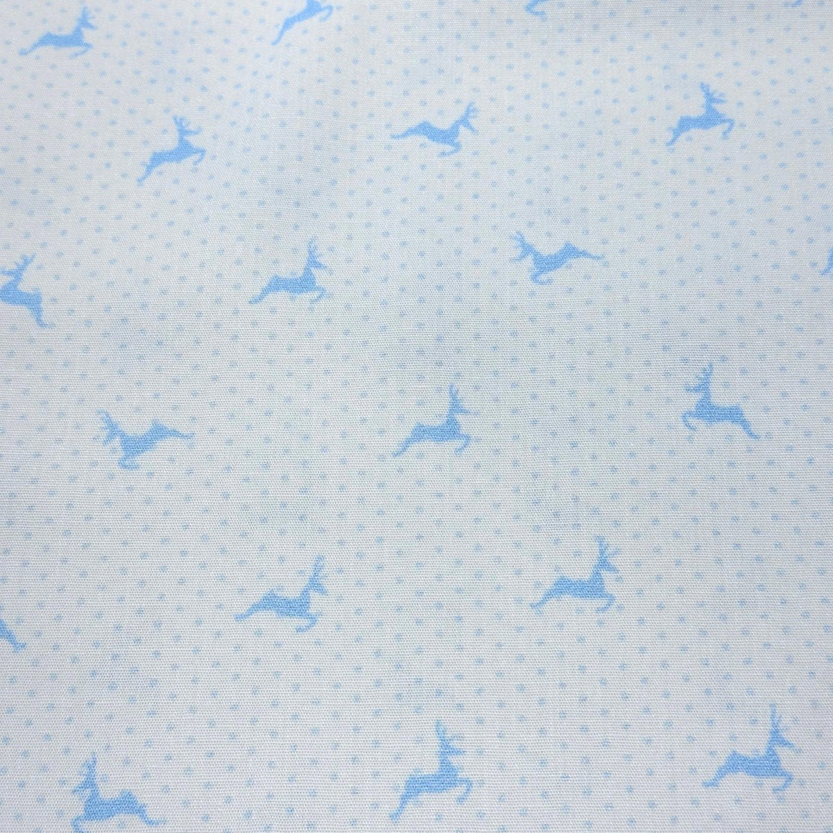 Light blue cotton fabric with small polka dots and scattered leaping reindeer silhouettes