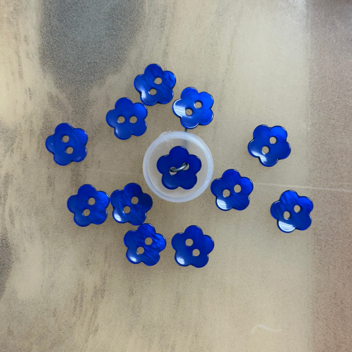 Royal blue flower-shaped plastic buttons arranged in a circle, two-hole design