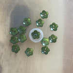 Green pearlescent flower-shaped plastic buttons with two holes, arranged in a circle