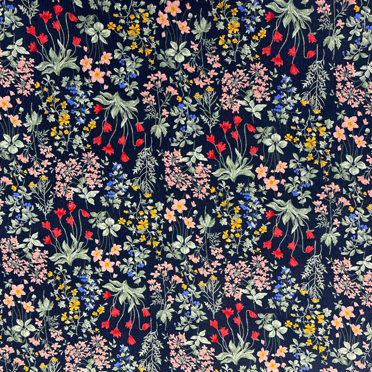 Navy corduroy fabric with dense multicolor wildflower print in pink, red, yellow, and blue